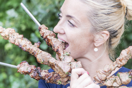 Portrait of a girl biting shish kebab