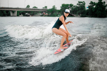 Fototapeta premium Young active girl in cap riding on the wakesurf