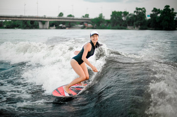 Young smiling active girl riding on the wakesurf
