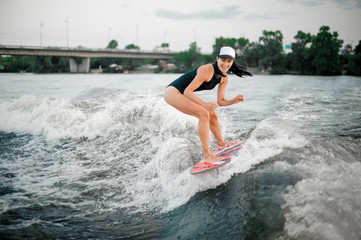 Young active girl riding on the wakesurf on the bending knees