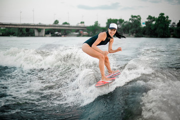 Fototapeta premium Young active girl riding on the wakesurf on the bending knees
