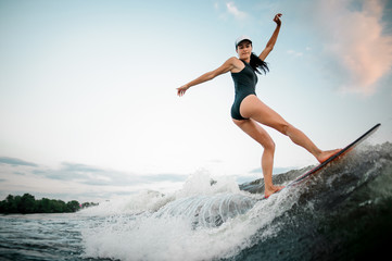 Rear view female wakesurfer riding on the wakesurf - obrazy, fototapety, plakaty