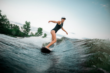 Side view young active woman riding on the wakesurf