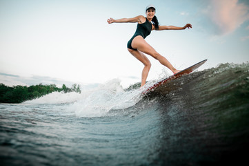 Rear view young active woman riding on the orange wakesurf