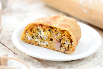 strudel with ham and cheese on a wooden board with flour