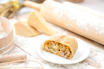 strudel with ham and cheese on a wooden board with flour