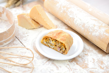 strudel with ham and cheese on a wooden board with flour