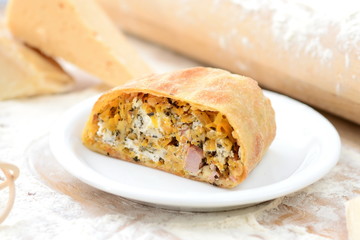 strudel with ham and cheese on a wooden board with flour