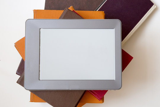 E-book reader device on desk in library. Alternative for traditional books