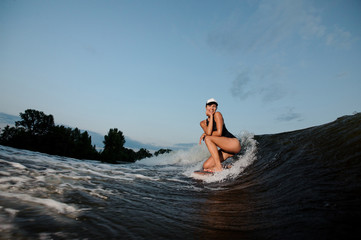Active woman standing on the one knee on the wakesurf
