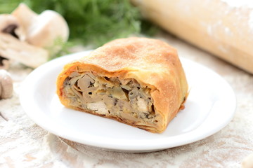 strudel with meat and mushrooms on a wooden board with flour