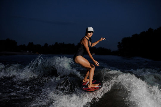 Young amazing girl riding on the orange wakesurf in the night