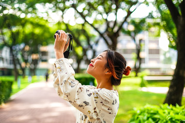 Asian girl student learn photography with small pocket camera outdoor at day in the park or university campus