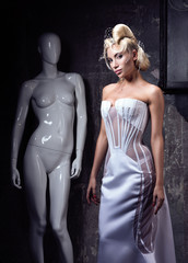The comparison of the woman and of the mannequin. Beautiful young woman in avant-garde dress and...