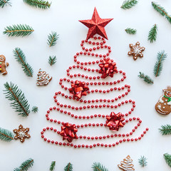 Creative idea for Christmas or New Year theme. A Christmas tree made of beads and a star on top. Next to it lie the traditional gingerbread and spruce branches for decoration.