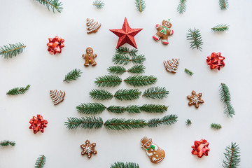 Creative idea for Christmas or New Year theme. A Christmas tree from spruce branches and a star on top. Nearby lie gingerbread cookies. Celebratory concept.