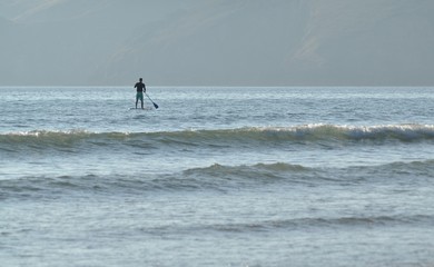 Homme sur une planche à rame en bord de mer