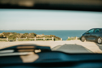 View through the rear window of the car to the parking lot in a row with the sea or the ocean in the summer. Conceptual picture of summer travel by car. © franz12