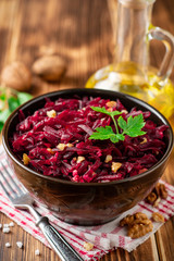 Beetroot salad with wallnuts and garlic in bowl on wooden table
