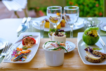 Plateau avec de petits plats: poivron farci, filet de sardines, crevettes, fromage de chevre, tartare de taureau, tomate verte farci, carpaccio d'agneau.