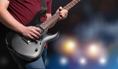 Plakat Male Guitarist playing music on dark background