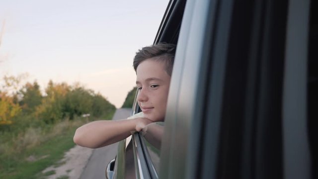 Teen boy looking out the car window. Summer trip with family