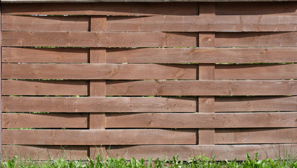 Wooden horizontal brown fence with grass from below