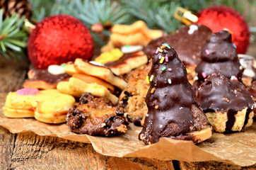 Close-up of christmas sweets with different types of candy on baking paper and Christmas decorations in background