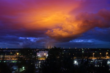 The sky at night with bright red clouds in the rays of the sun.