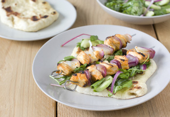 Chicken tikka on skewers, naan flat bread, onion and salad