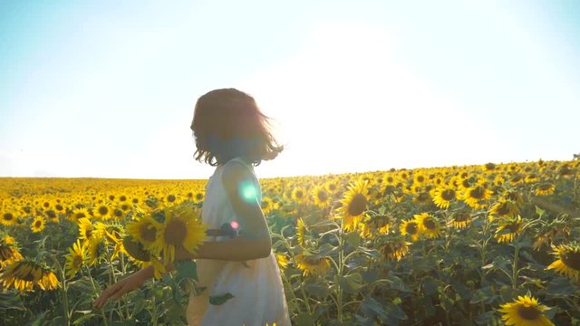 Happy little girl running happy free across lifestyle the field with sunflowers. slow motion video . smelling big sunflower on summer field. Delight of a pleasant smell. Summer holiday. concept