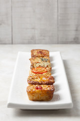 Individual mini quiche pies on a white rectangular plate