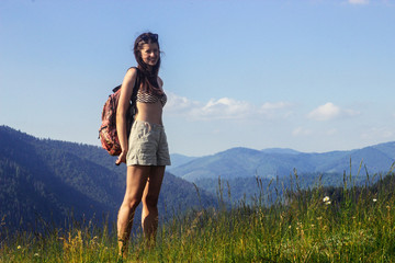 happy beautiful girl hipster traveling on top hill on background of amazing sky and mountains in summer