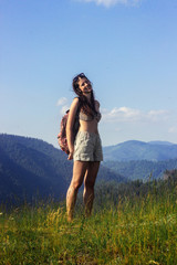 happy beautiful girl hipster traveling on top hill on background of amazing sky and mountains in summer