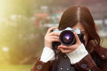 stylish happy girl traveler with photo camera on the background of sunny mountains taking photos