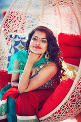 Fototapeta premium portrait of beautiful indian woman in traditional dress relaxing on sofa
