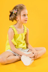 Obraz na płótnie Canvas A teenage girl is sitting on a yellow background.