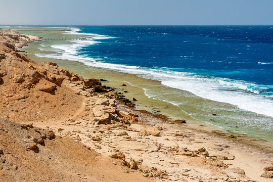 A Long View of the Desert and Wide Coral Reef with Large Foamed Waves and Lonely Piers at Calimera Habiba Beach Resort