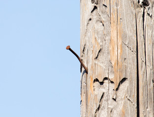 Wooden table with a protruding nail against the blue sky