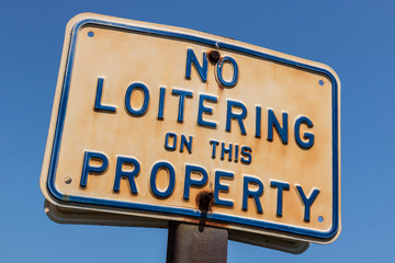 Aged and weathered No Loitering on this Property sign I