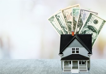 Dollar bills and house model on light