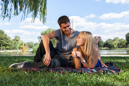 Smiling Young Couple Enjoying Picnic with Washington Monument in Background