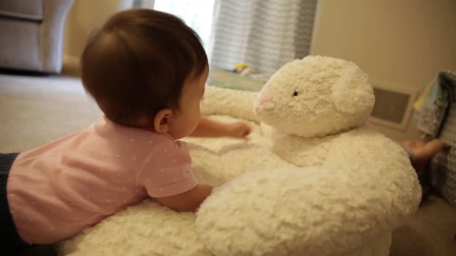 Happy Baby Playing and Snuggling on Stuffed Lamb Toy