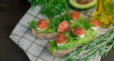 Avocado toast, cherry tomato on wooden background. Breakfast with toast avocado, vegetarian food, healthy diet concept.