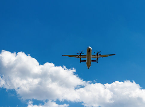 Propeller aircraft plane in clear blue sky above white clouds