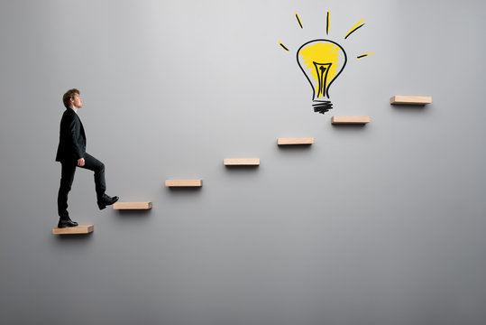 Businessman climbing steps towards light bulb