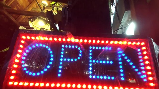 Restaurant Sign Blinking Open With Traffic In The Background.