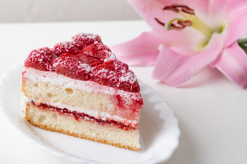 Strawberry cake on a white background and a pink flower
