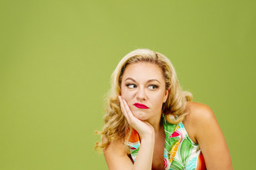 Portrait of an envious woman in bad mood looking right, isolated on green studio background