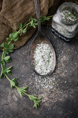Oregano Herb Salt in Tarnished Spoon on Black Background with Fresh Sprig of Oregano